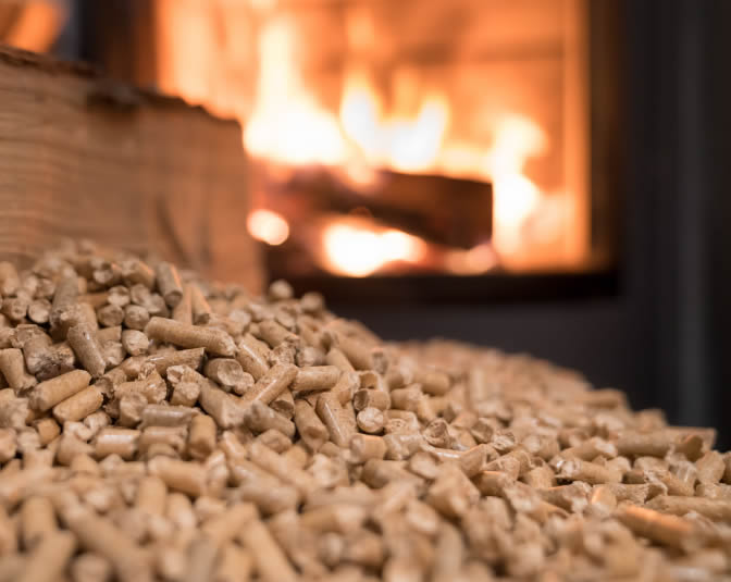 ellets de madera para estufas y calderas de biomasa junto a una estufa encendida.